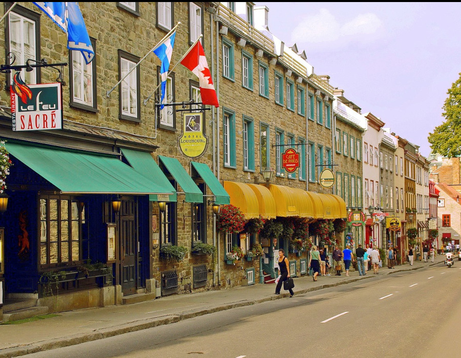 Une vue pittoresque de la basse-ville du Vieux-Québec, au Canada, avec des bâtiments historiques aux façades colorées sous un ciel bleu clair.