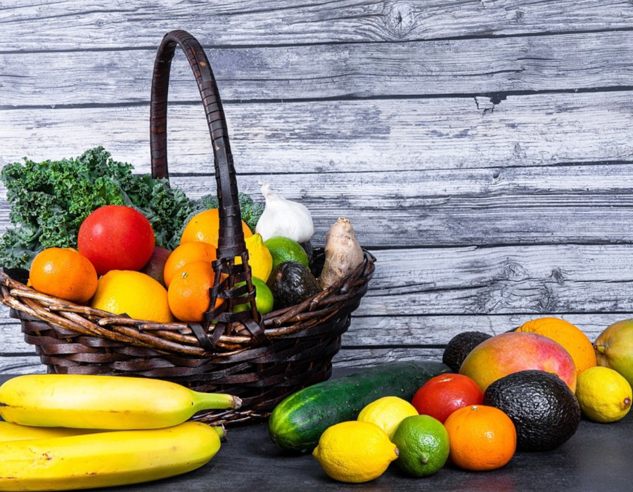 A vibrant and colorful assortment of fresh fruits neatly arranged in a wicker basket. The basket includes a variety of fruits such as strawberries, blueberries, oranges, grapes, and kiwis, showcasing a rich palette of colors and textures. The fruits appear ripe and juicy, suggesting freshness and organic quality. The setting is outdoors, with natural light enhancing the vividness of the fruits' colors, inviting the viewer to enjoy the healthy and natural bounty.