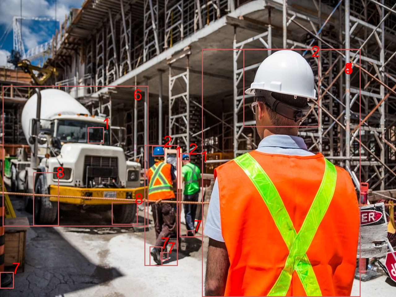 A construction worker wearing a yellow hard hat and high-visibility safety vest is focused on his work at a construction site. 